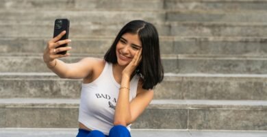 a woman sitting on steps taking a picture with her cell phone